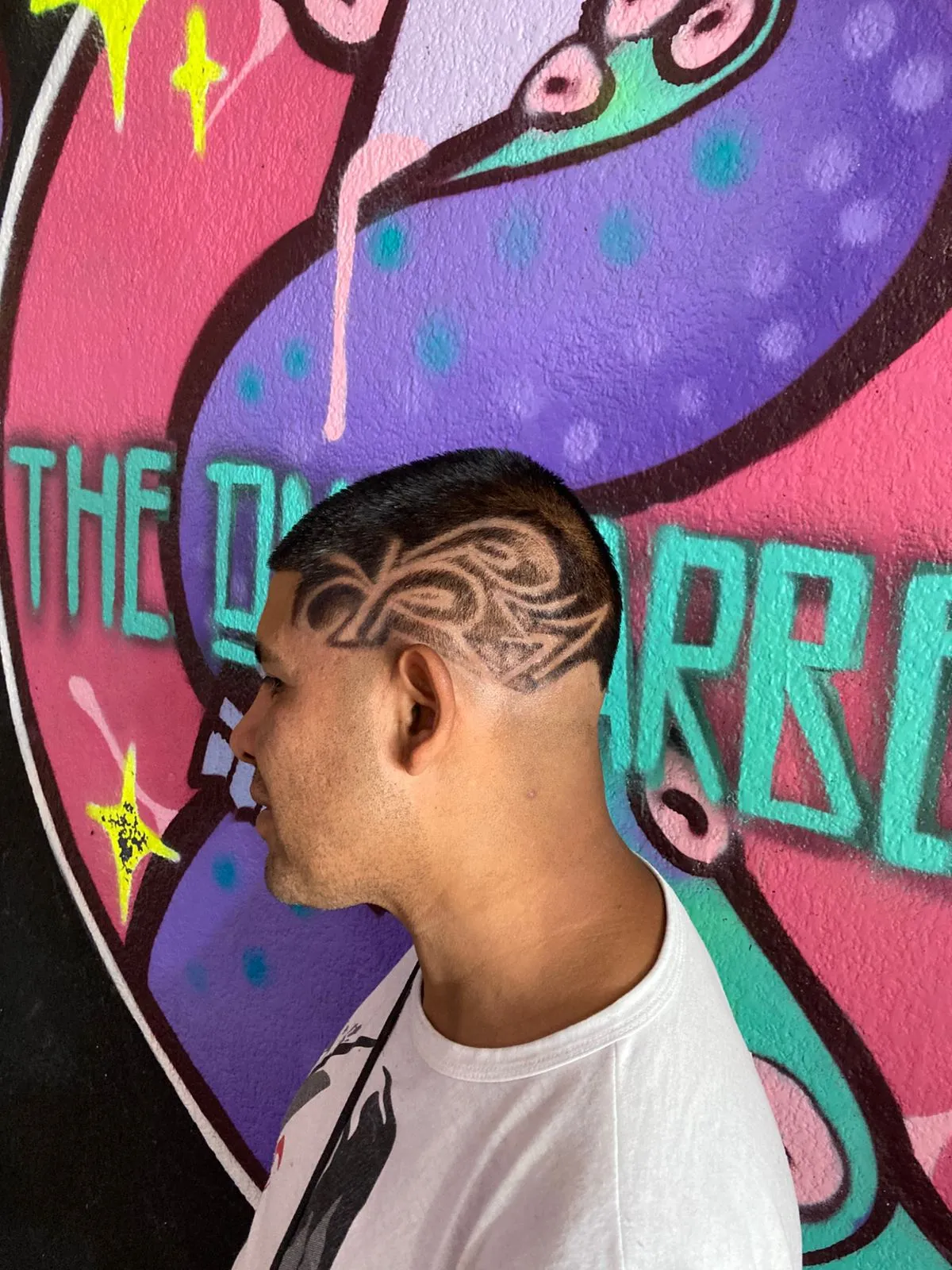 Corte con diseño frente al mural — The OneBarber Shop